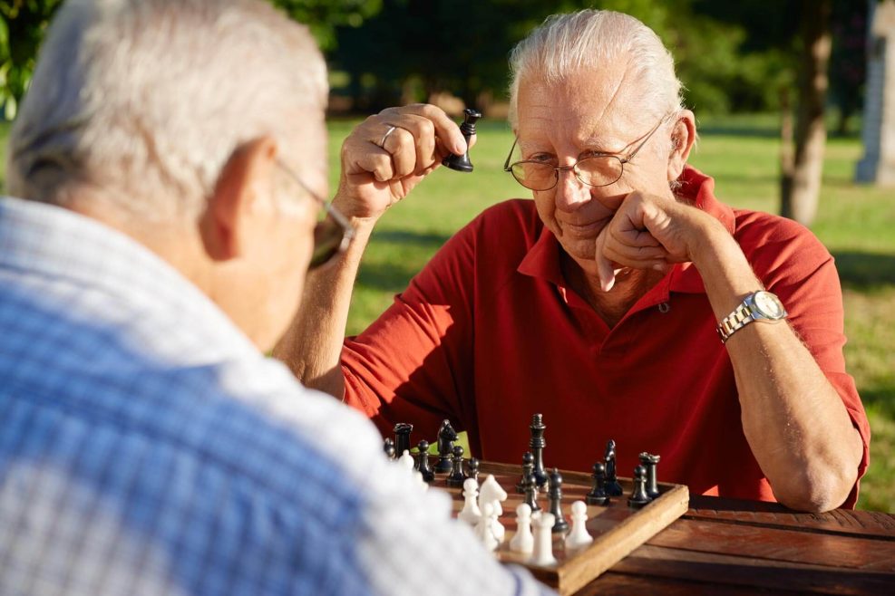 Active retired people, old friends and free time, two senior men having fun and playing chess at park. Head and shoulders