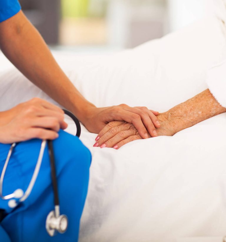 medical doctor holding senior patient's hands and comforting her